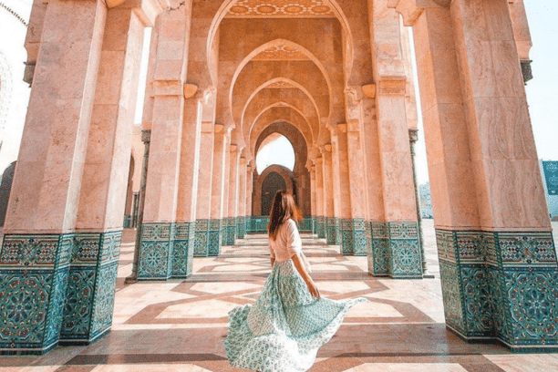 Traveler walking through the magnificent arches of the Hassan II Mosque in Casablanca, Morocco, during a private Morocco tour.