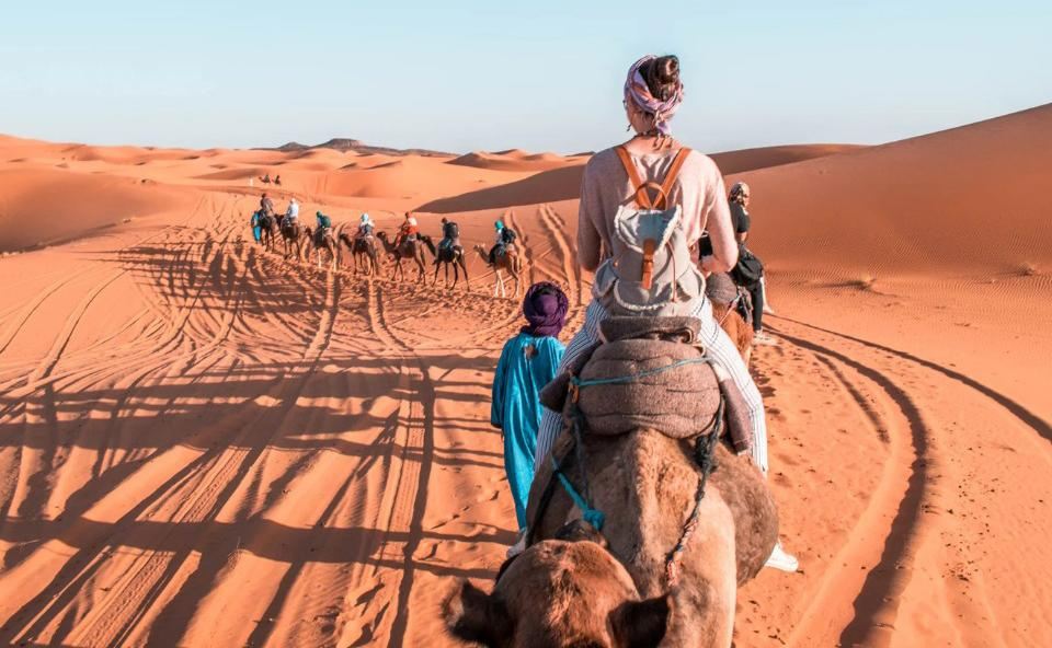 Travelers riding camels in the Sahara Desert during a Merzouga camel trekking tour in Morocco