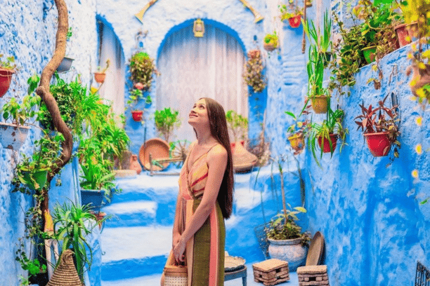 Traveler exploring a charming blue alley filled with colorful plants in Chefchaouen, Morocco, during a private Morocco tour.