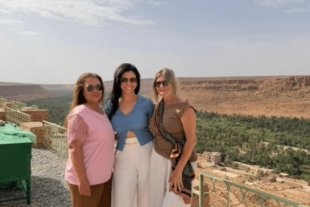 Travelers enjoying the panoramic view of Ziz Valley, a lush oasis surrounded by desert landscapes in southeastern Morocco.