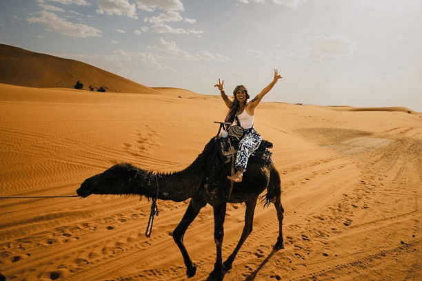 Traveler riding a camel through the Sahara Desert in Merzouga Morocco